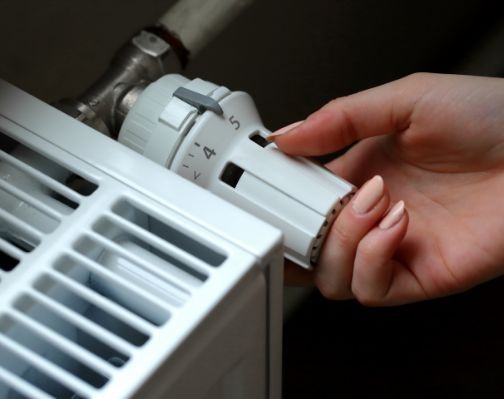 Hand, die eine Heizung regelt